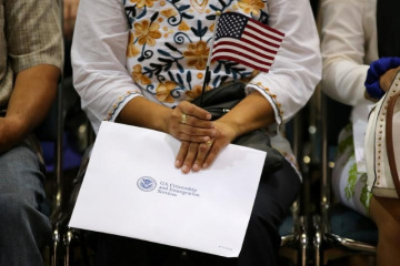 An attendee holds her new country's flag and her naturalization papers as she is sworn in during a U.S. citizenship ceremony in Los Angeles, U.S., July 18, 2017.    REUTERS/Mike Blake