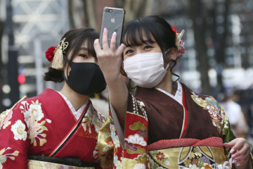 Kimono-clad women wearing face masks to protect against the spread of the coronavirus pose for a selfie together following a Coming-of-Age ceremony in Yokohama, near Tokyo, Monday, Jan. 11, 2021. (AP Photo/Koji Sasahara)